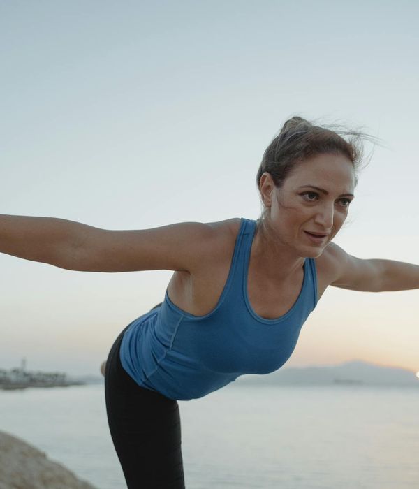 Woman in a calming yoga pose, beginning her morning routine.